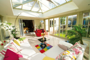 Interior shot of a conservatory decorated with colourful sofas, rugs, cushions, and a lamp.